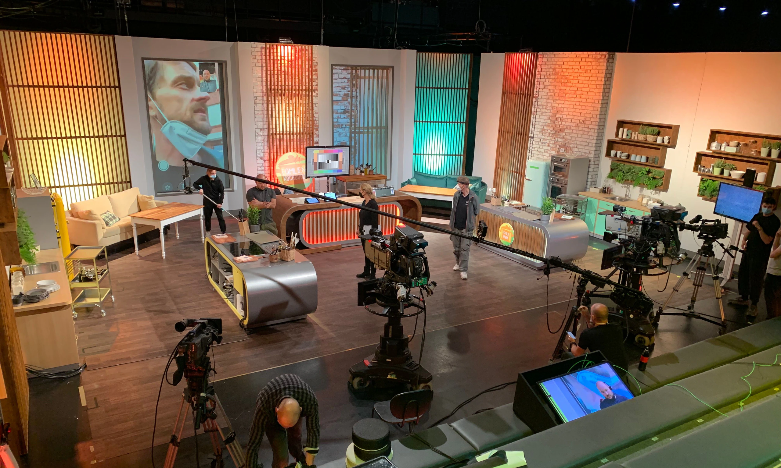 Fernsehstudio einer Kochshow beim Aufbau: Küchenkulisse, Studiokameras und Kran, Team am Set.